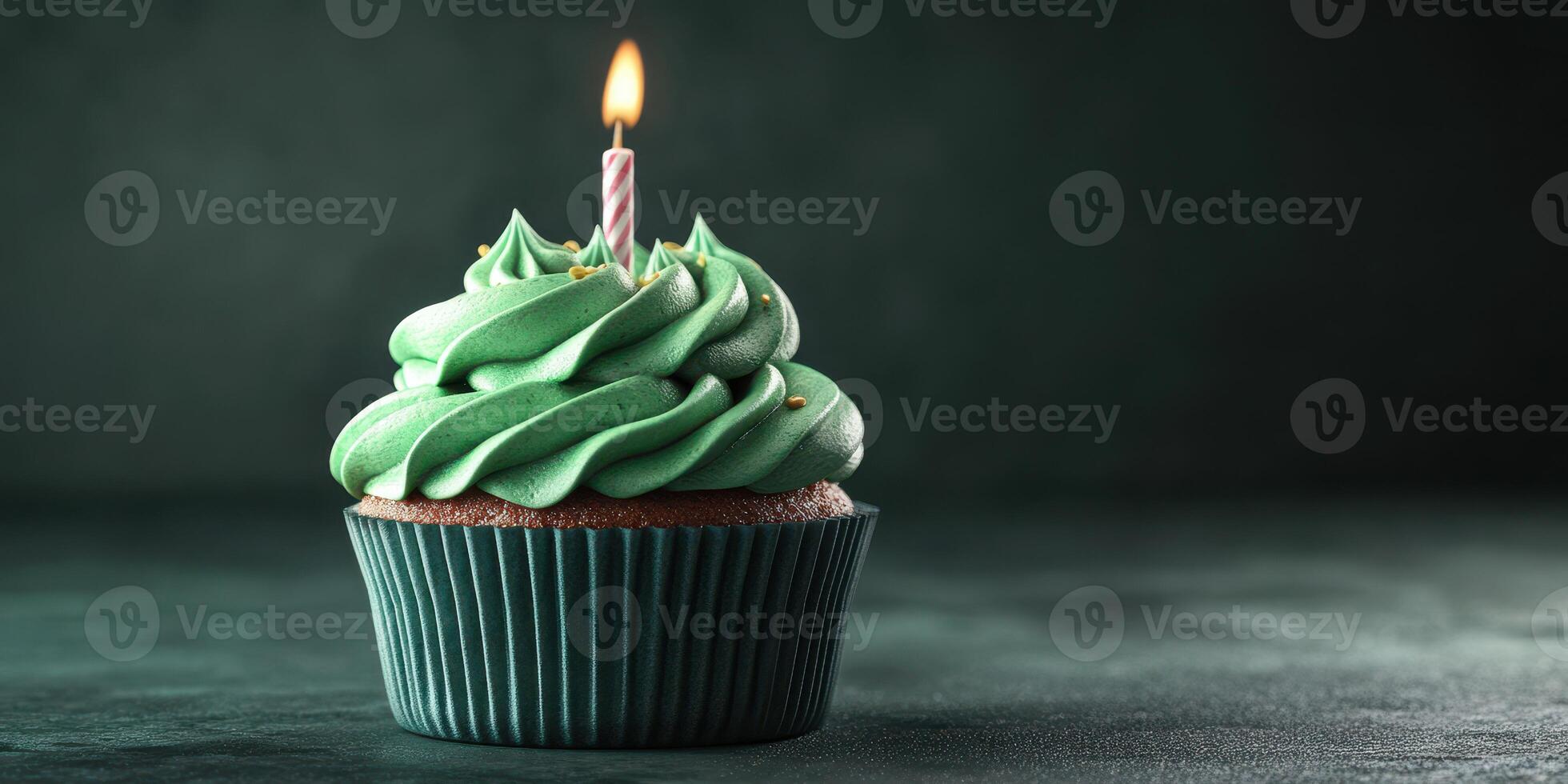 Cupcake with green frosting and a candle ready for celebration in a dimly lit setting photo