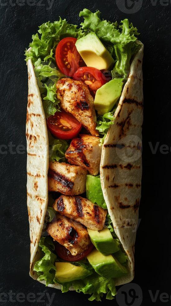 Grilled chicken wrap filled with fresh vegetables served on a dark background photo