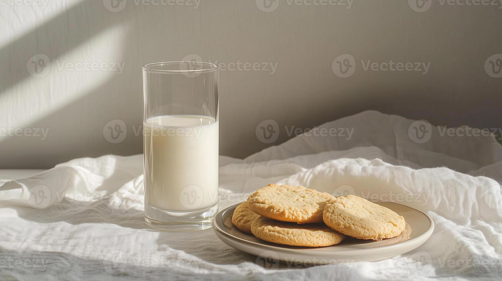 early morning on the table there is a glass glass with milk oatmeal cookies in a plate on a white linen cloth photo