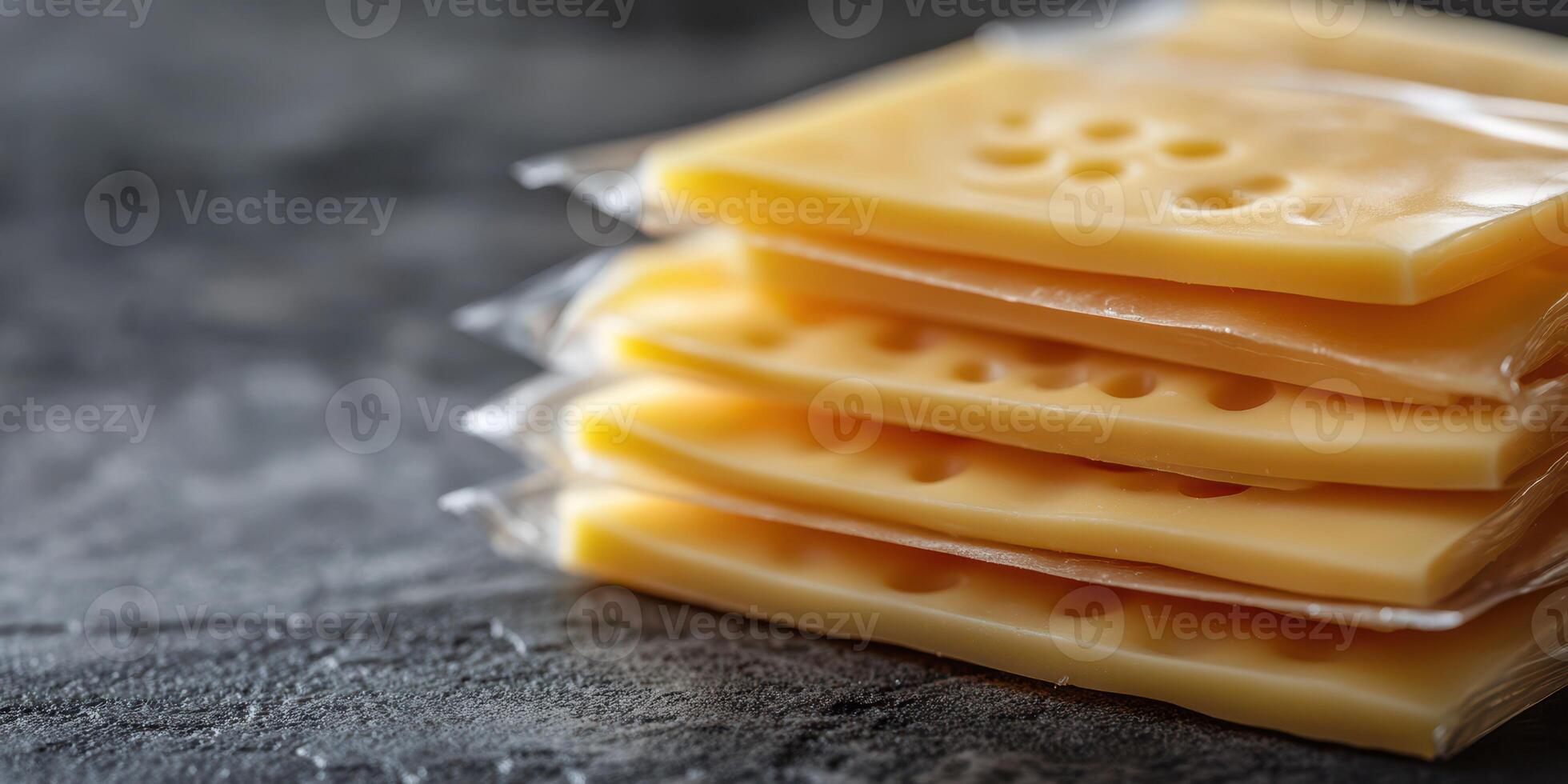 Slices of yellow cheese packaged neatly on a gray surface ready for culinary uses or snacks photo