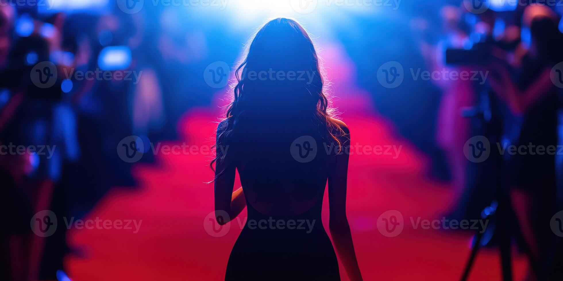 Elegantly dressed individual walks confidently on red carpet at nighttime event surrounded by flashing cameras and bright lights photo