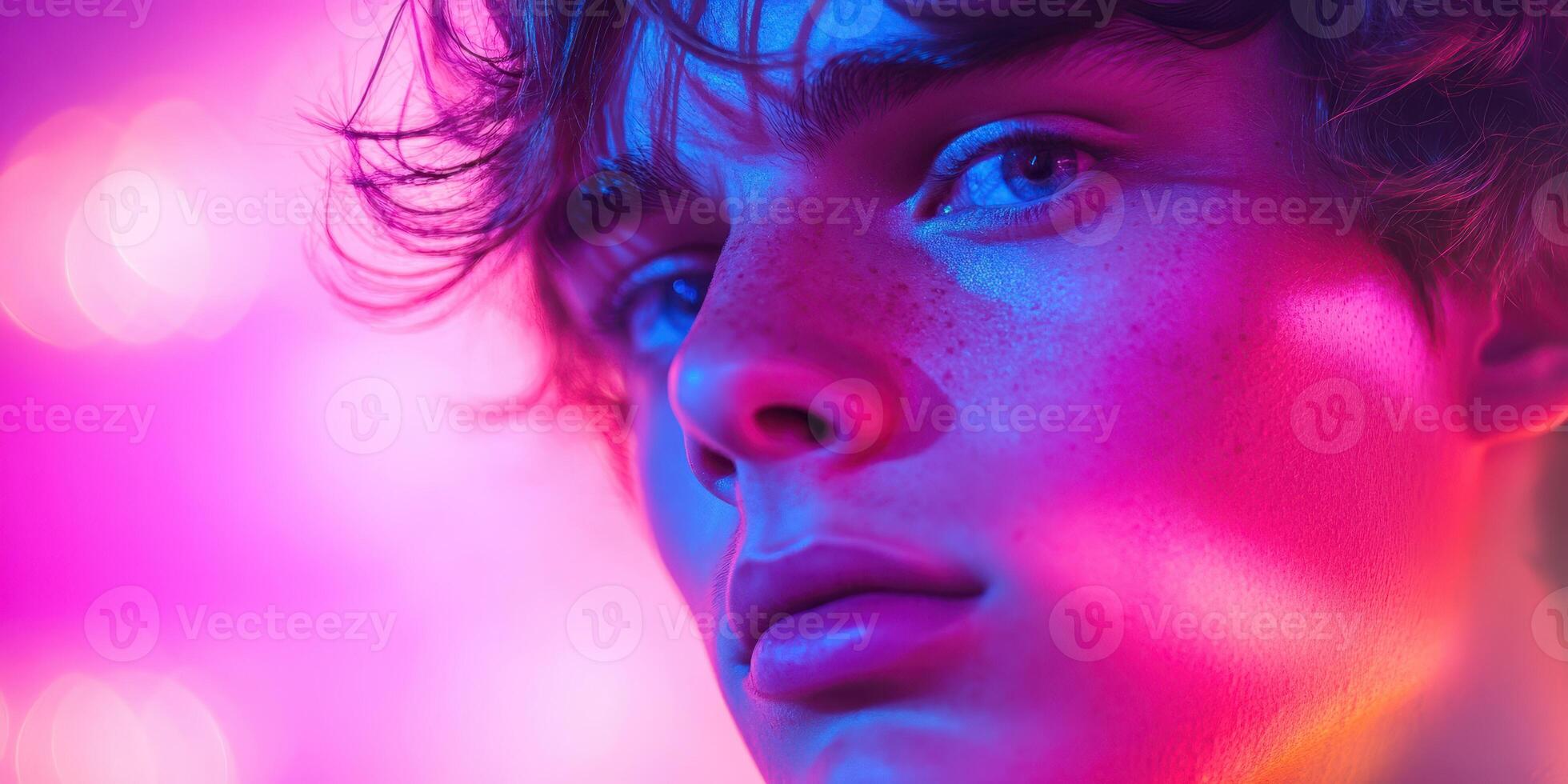Close-up portrait of a young man illuminated by vibrant purple and pink lights during a creative photoshoot photo