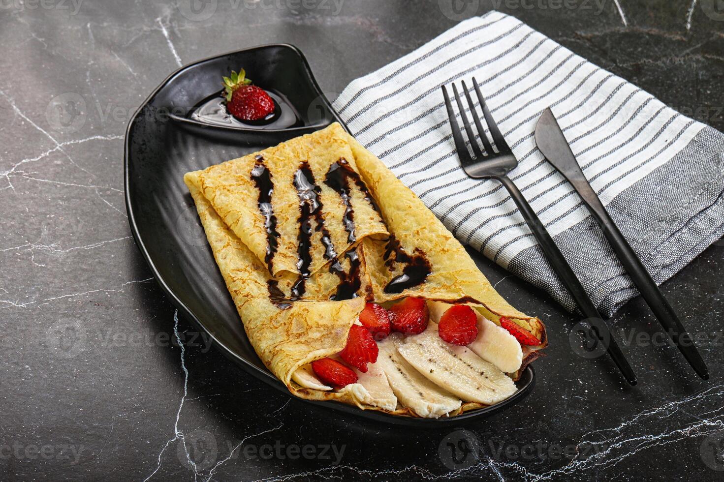A plate with a crepe and strawberries on it photo