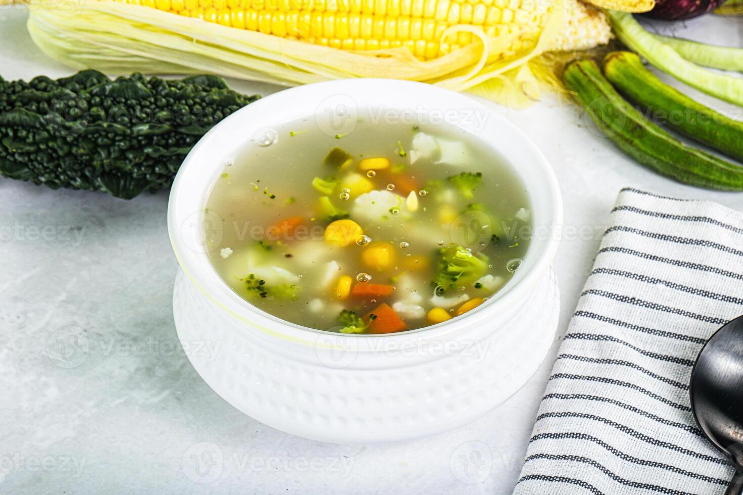 A bowl of soup with corn, broccoli and other vegetables photo