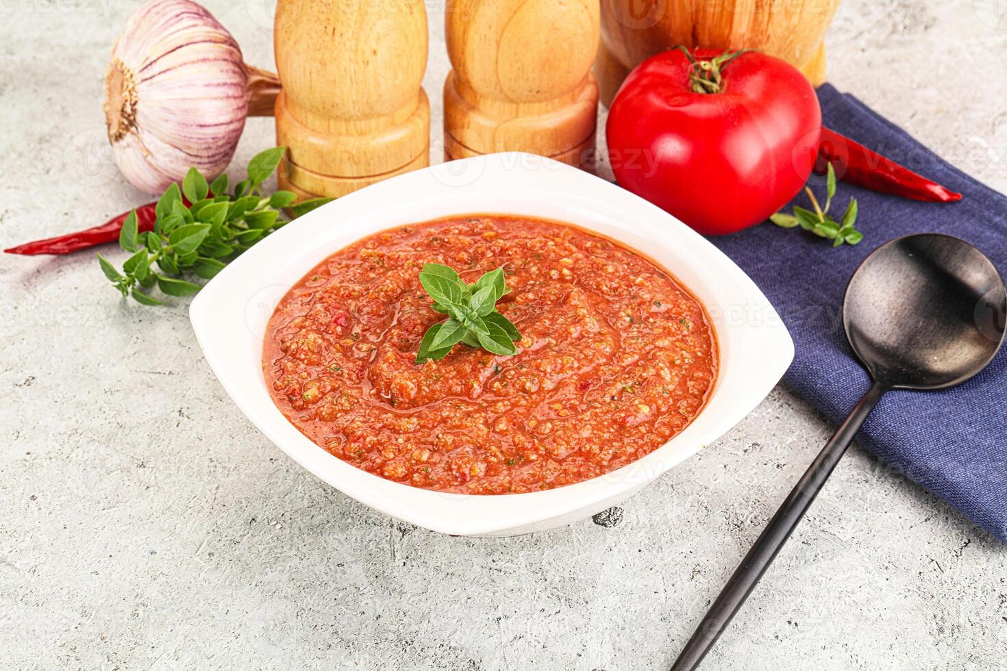 A bowl of tomato sauce with a spoon and a knife photo