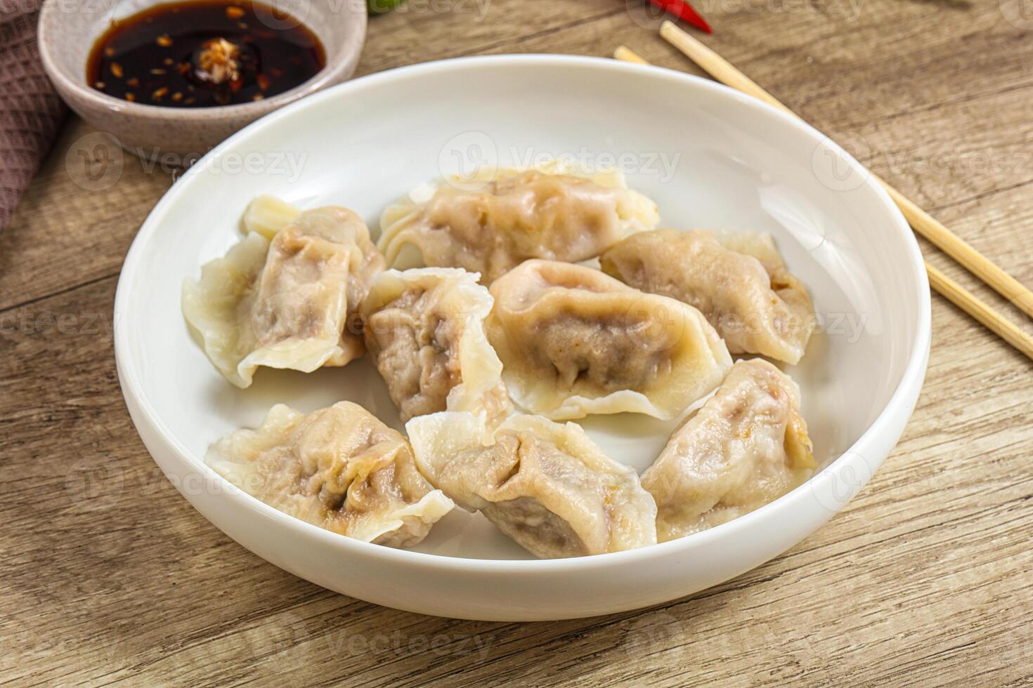 A bowl of dumplings with chopsticks and sauce photo