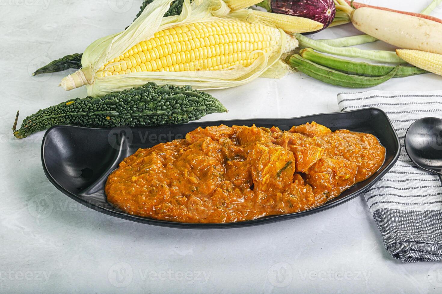 A bowl of food with a spoon and a corn cob photo