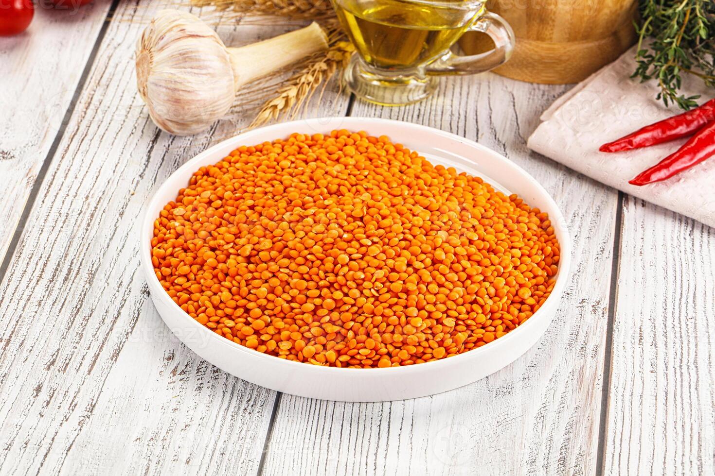 A bowl of red lentils on a table next to other ingredients photo