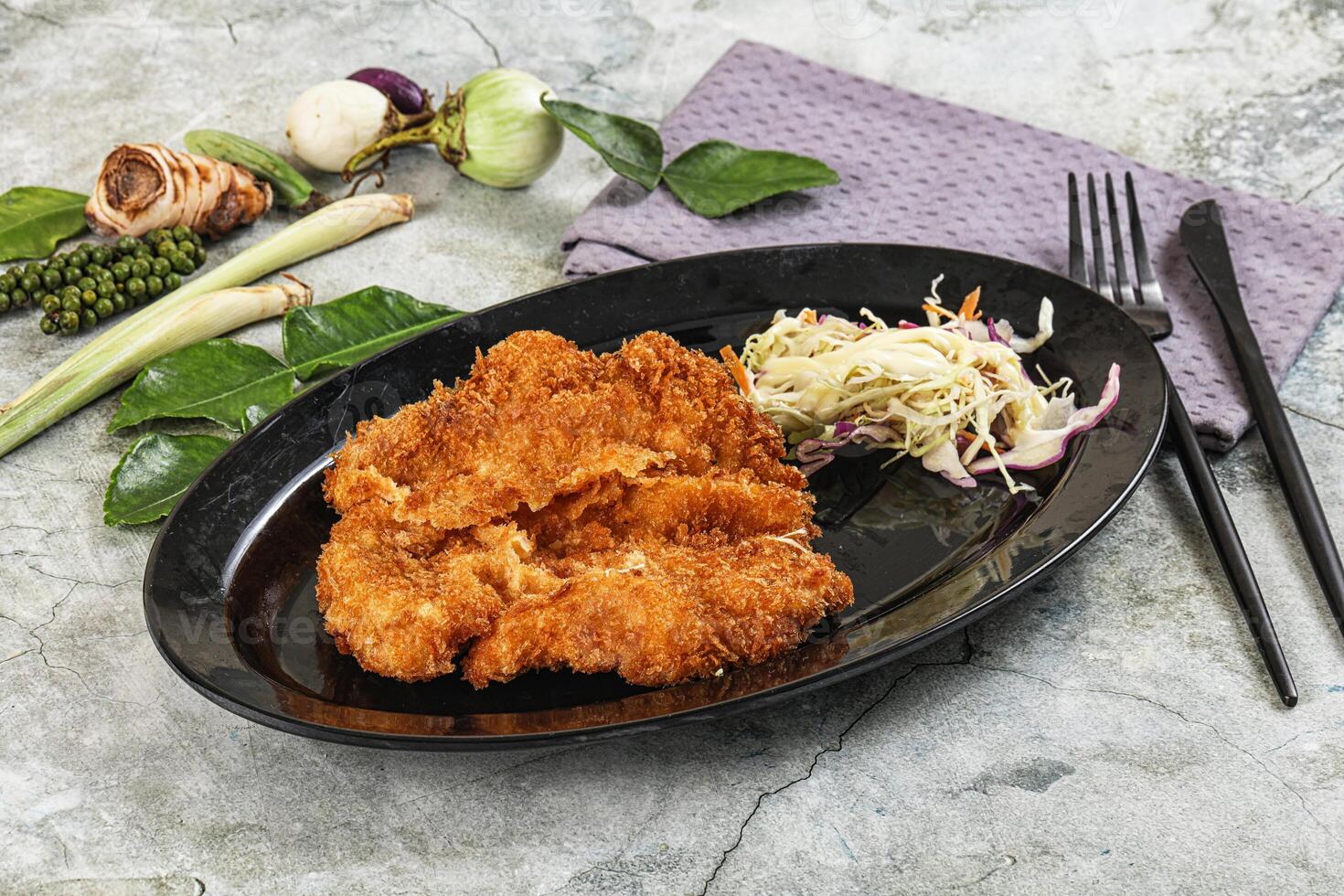 Fried chicken on a black plate with vegetables and a fork photo