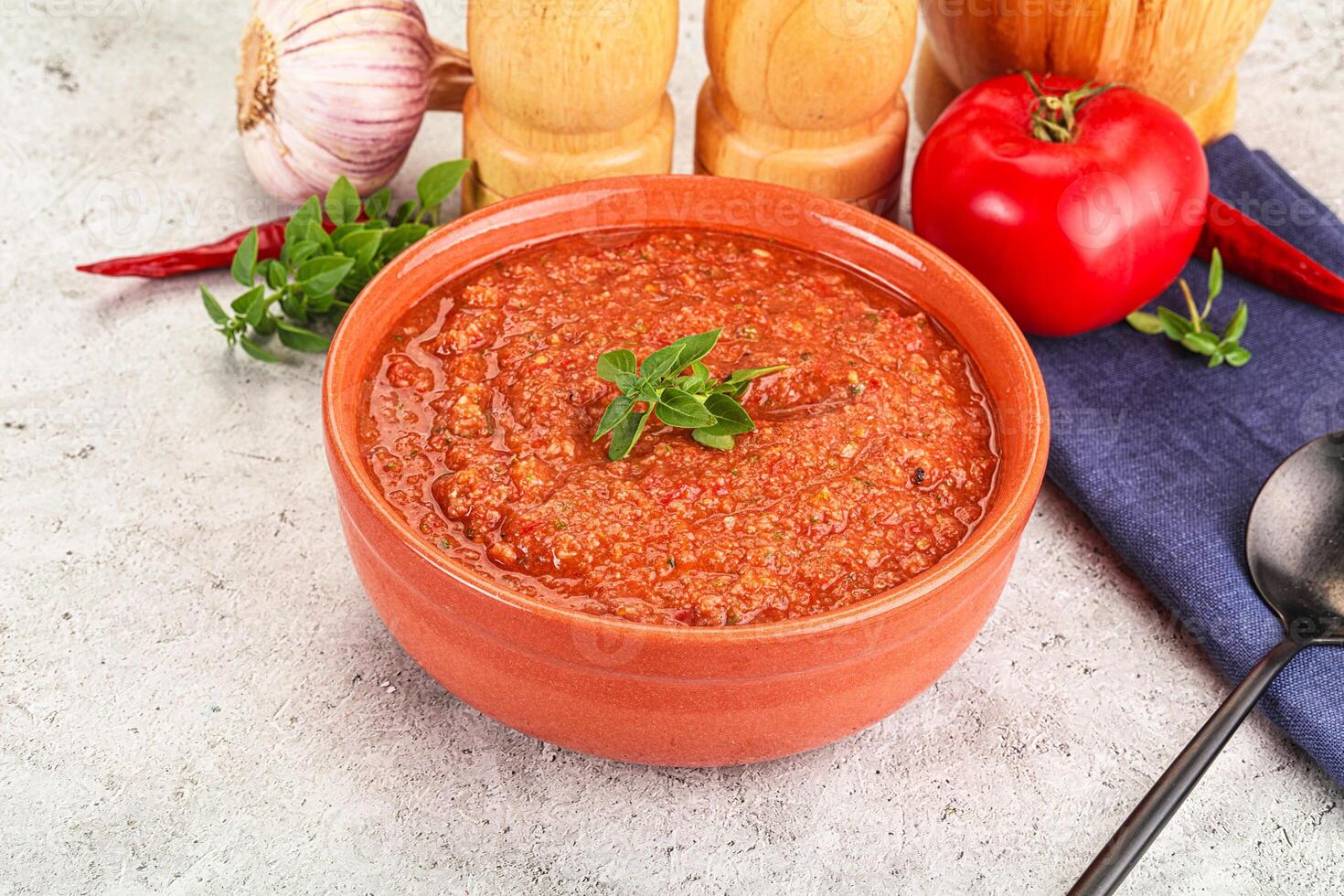 A bowl of tomato soup with a spoon and a knife photo