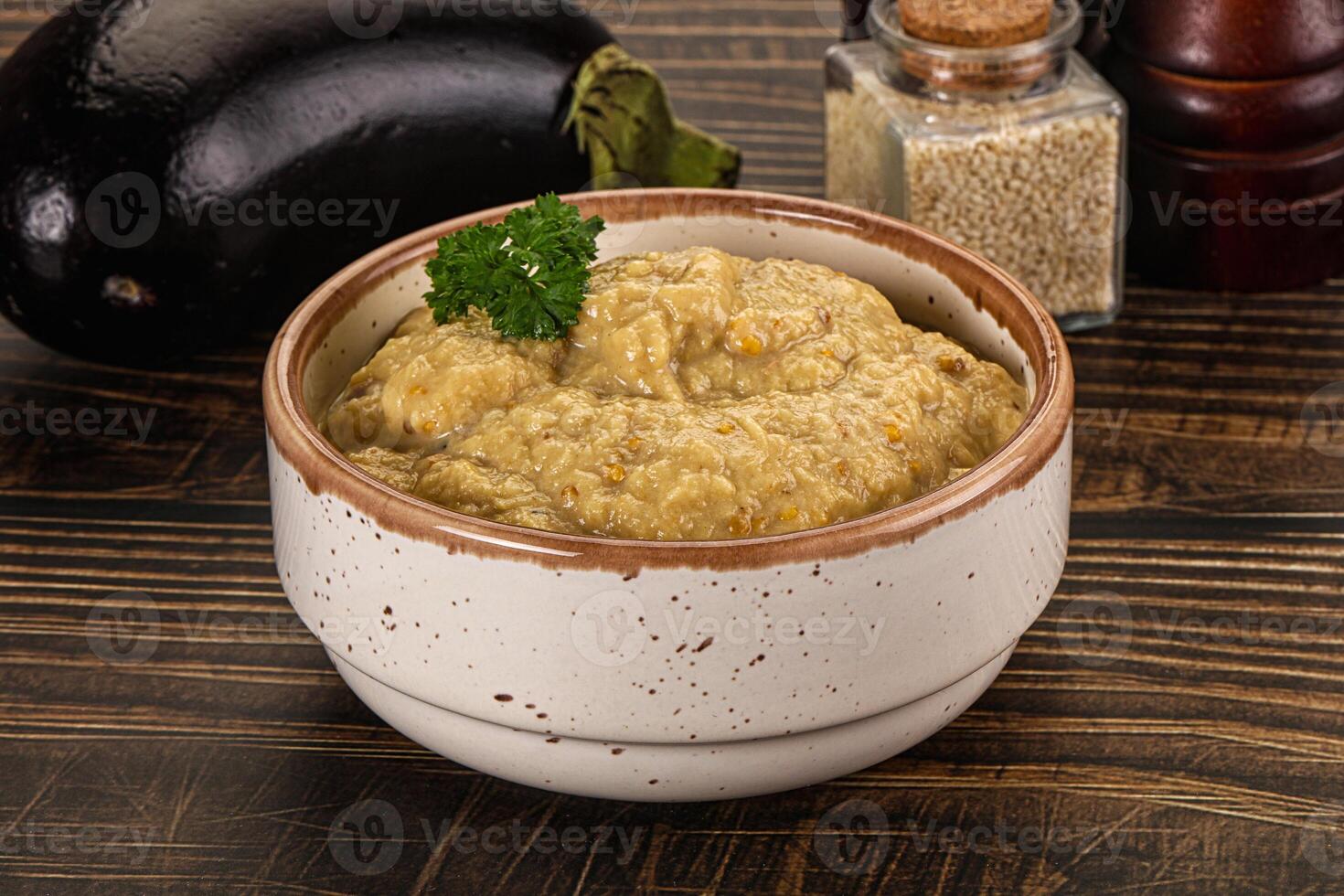 A bowl of food sitting on a table next to a bowl of eggplant photo
