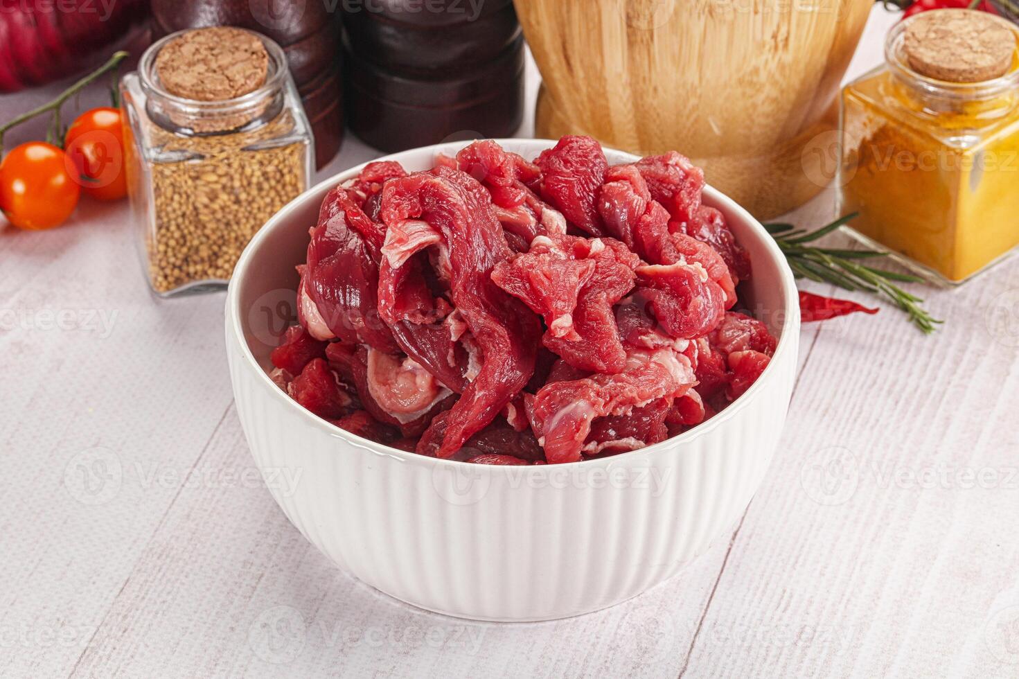 Raw meat in a bowl on a white table photo