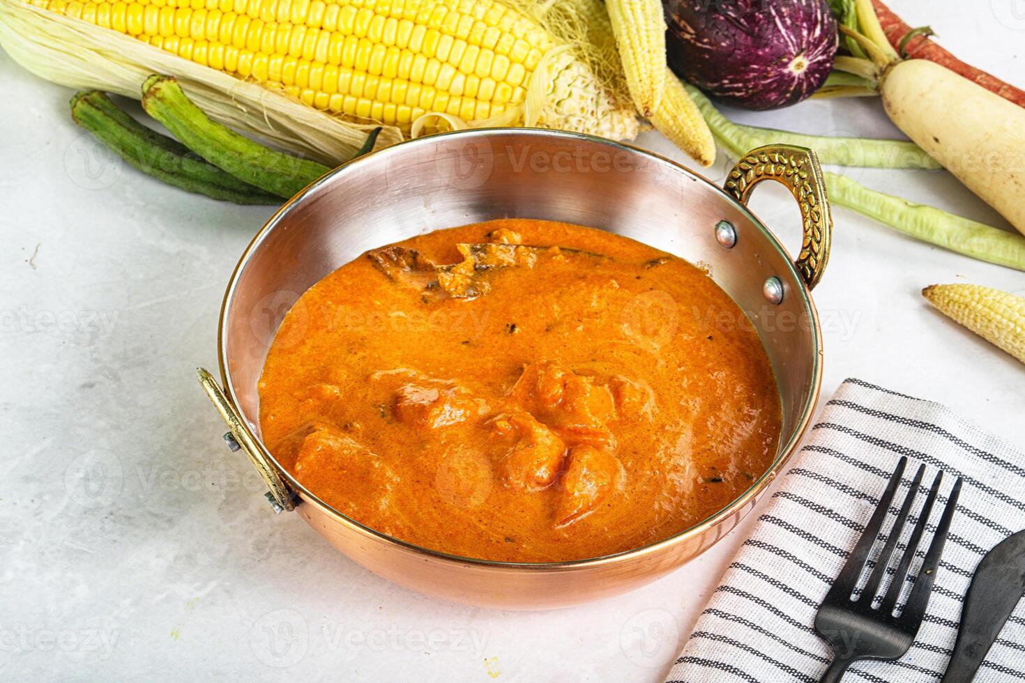 A bowl of soup next to a corn cob photo
