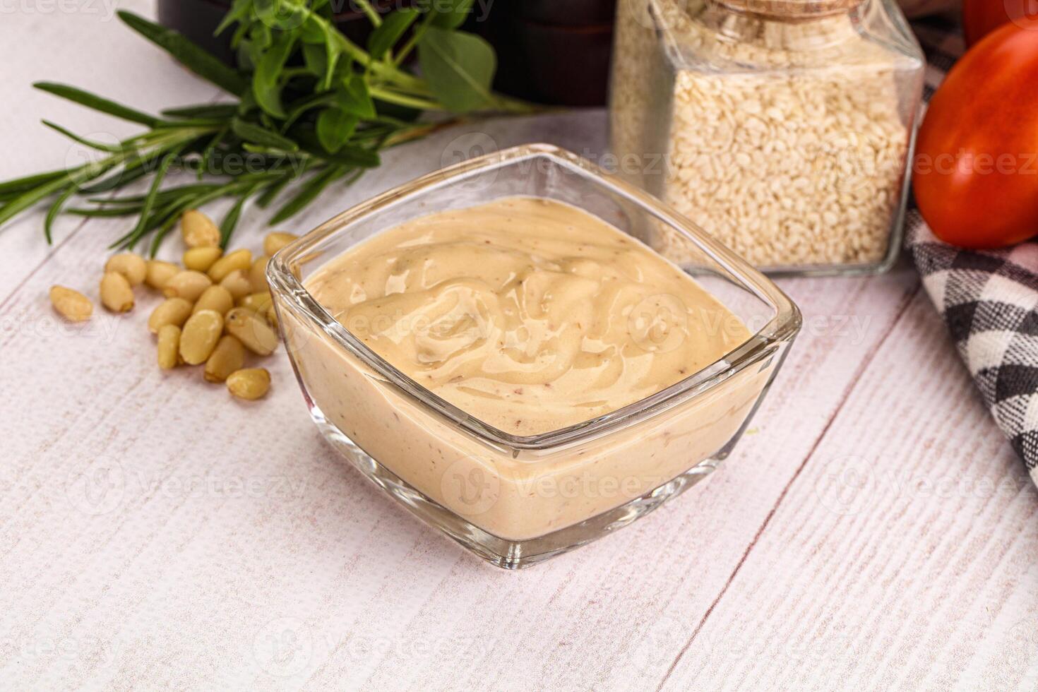 A bowl of peanut butter and other ingredients on a white table photo
