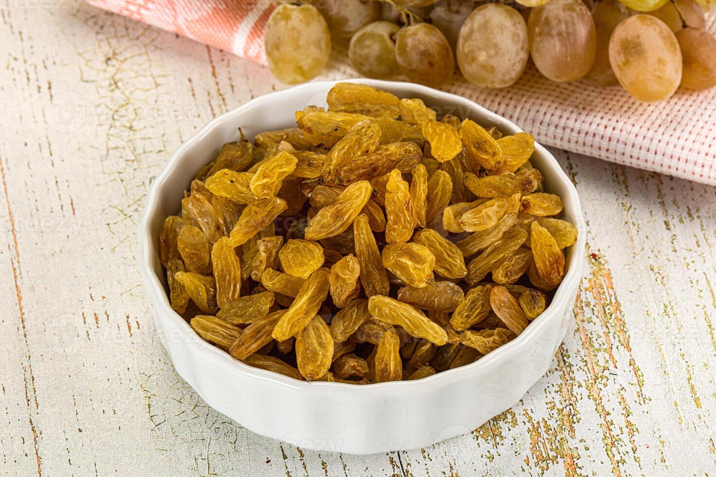 A bowl of raisins and a bowl of grapes photo