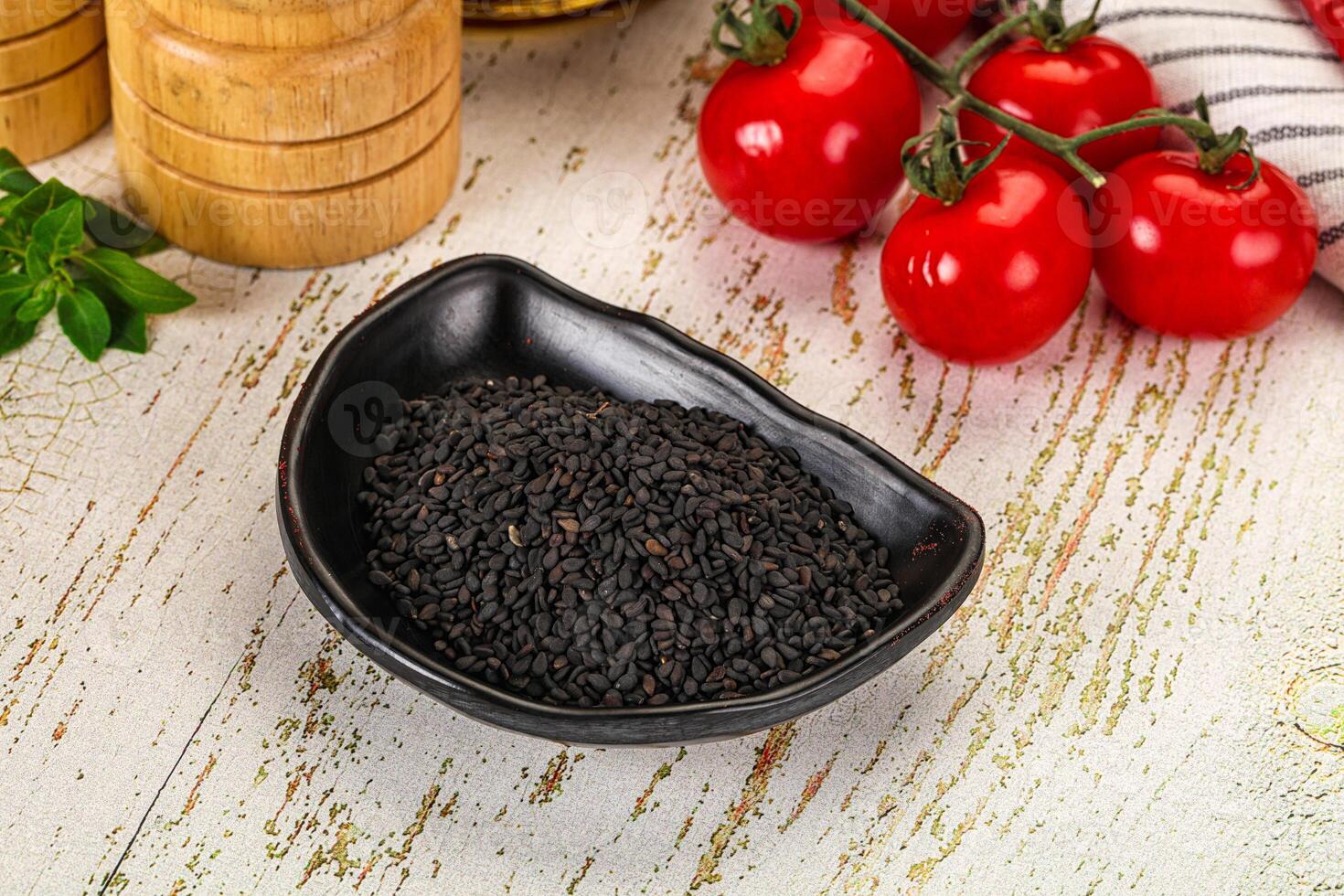 Black sesame seeds in a bowl on a wooden table photo