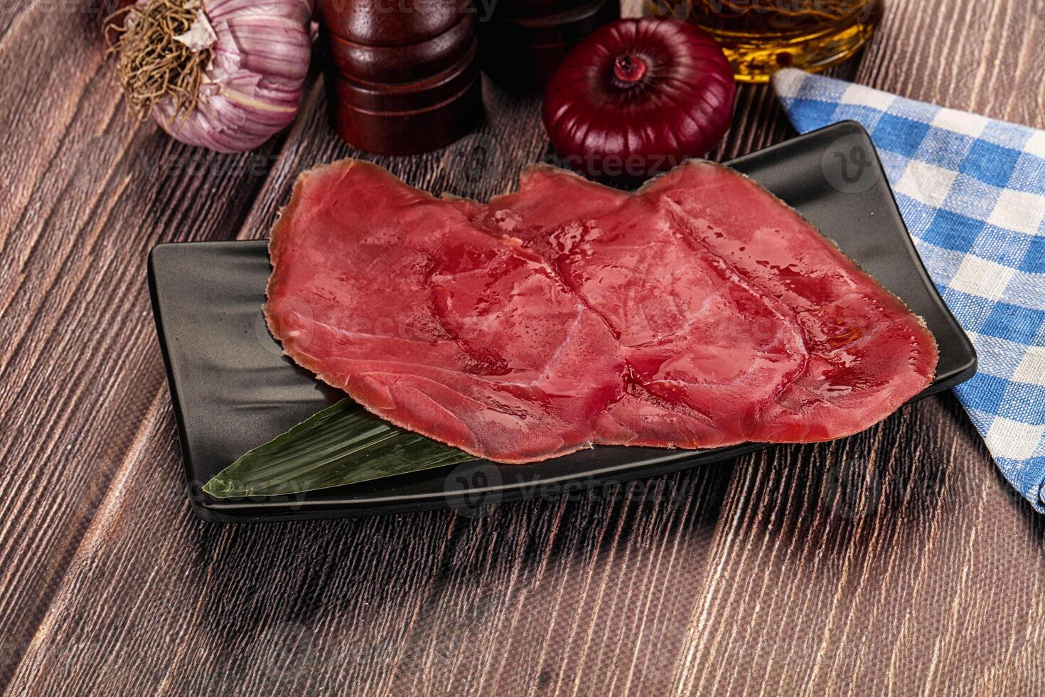 A piece of meat on a plate with some spices and other ingredients photo