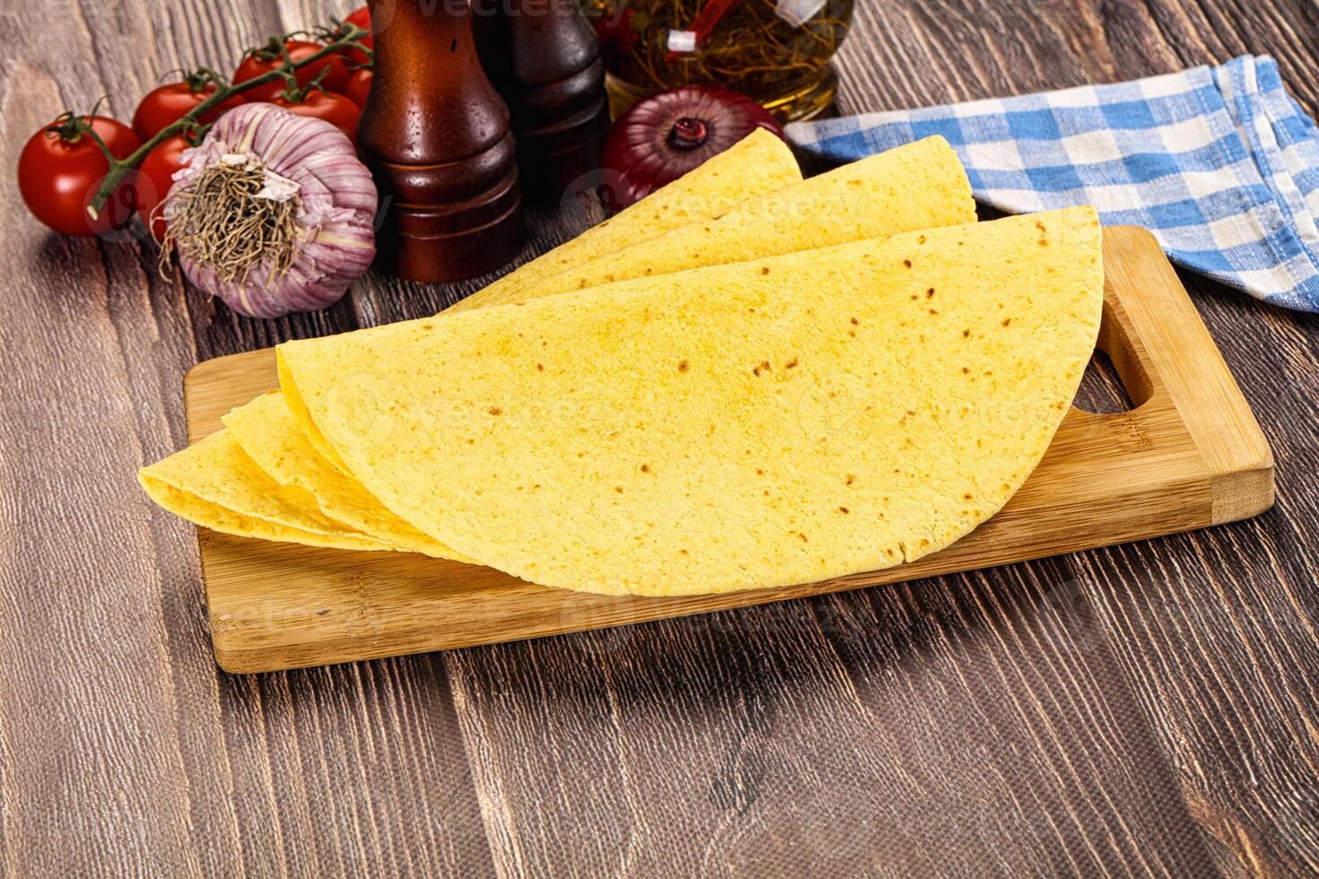 A tortilla on a cutting board with tomatoes and spices photo