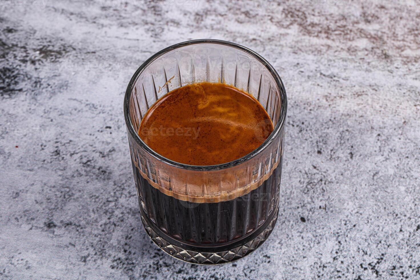 A glass of coffee sitting on a table photo