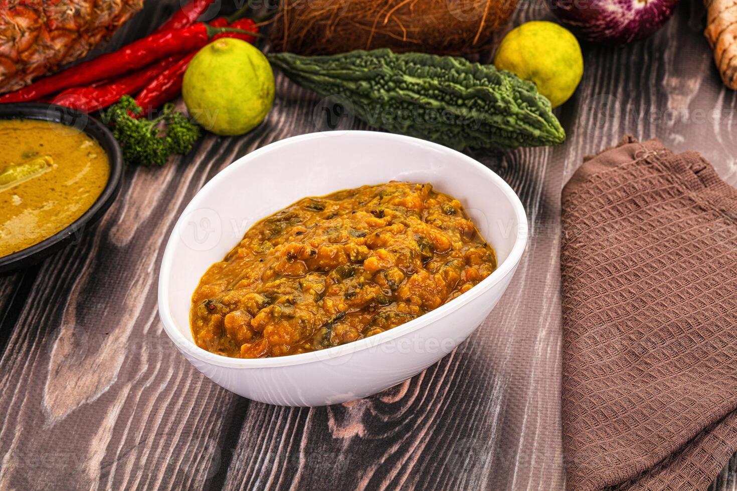 A bowl of food sits on a table next to a plate of vegetables photo