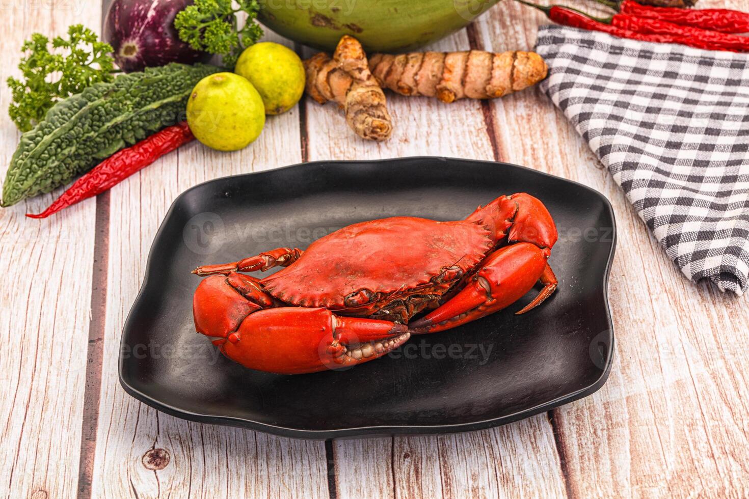 A crab on a plate with other vegetables and spices photo