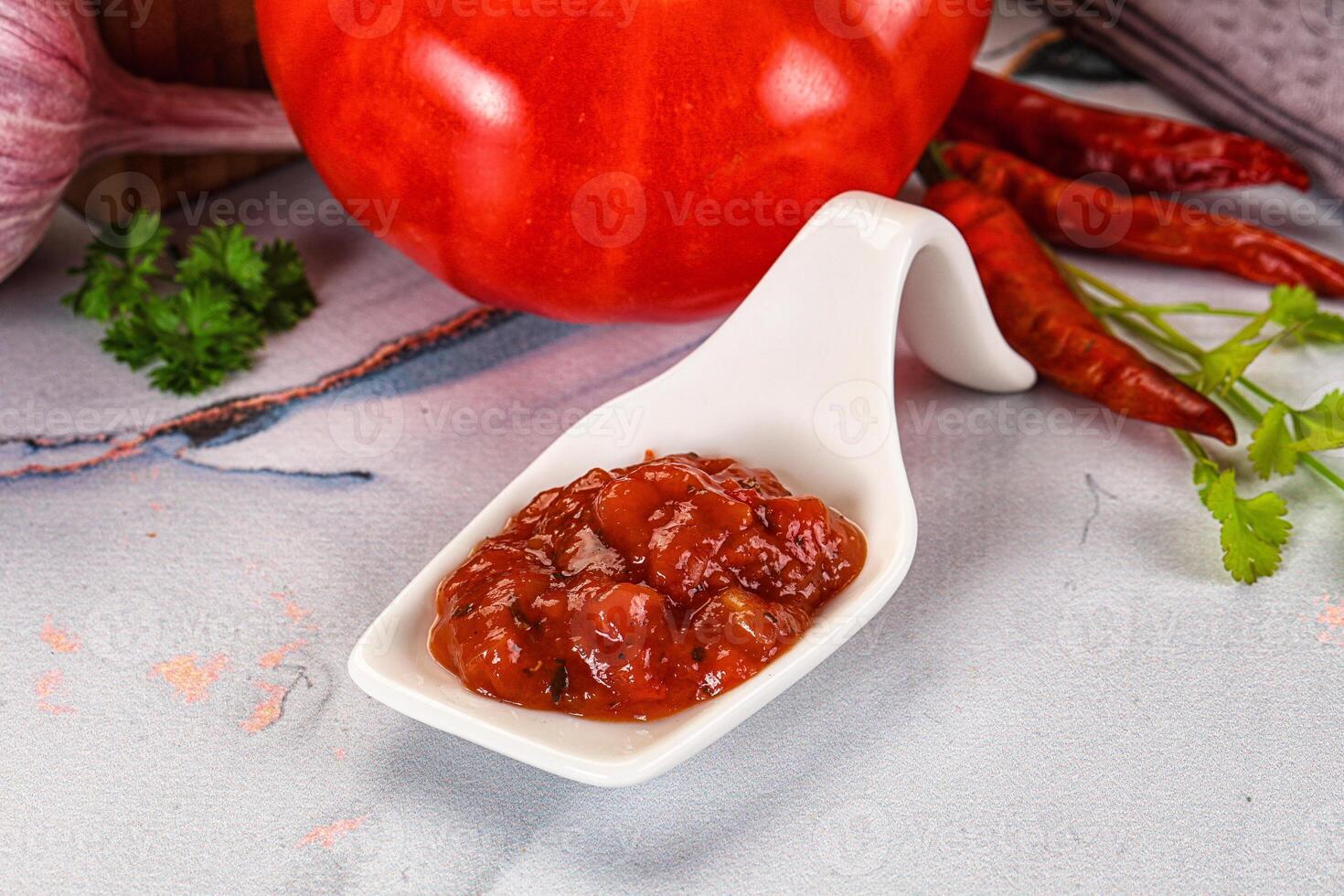A white spoon with a tomato and some other ingredients photo