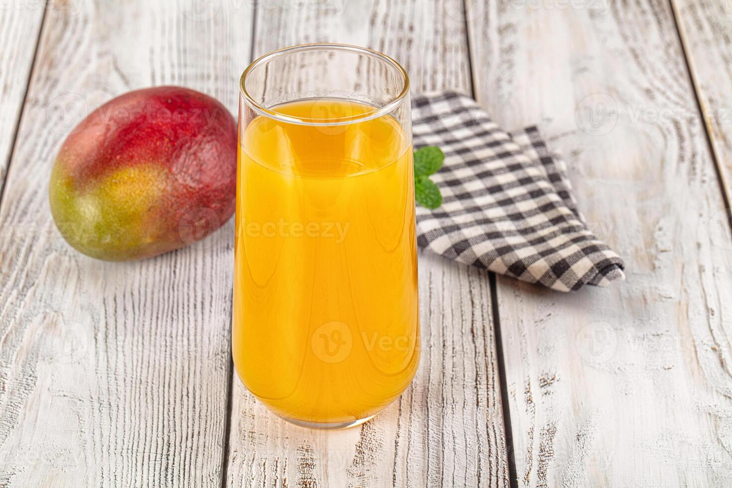 A glass of orange juice next to a mango photo