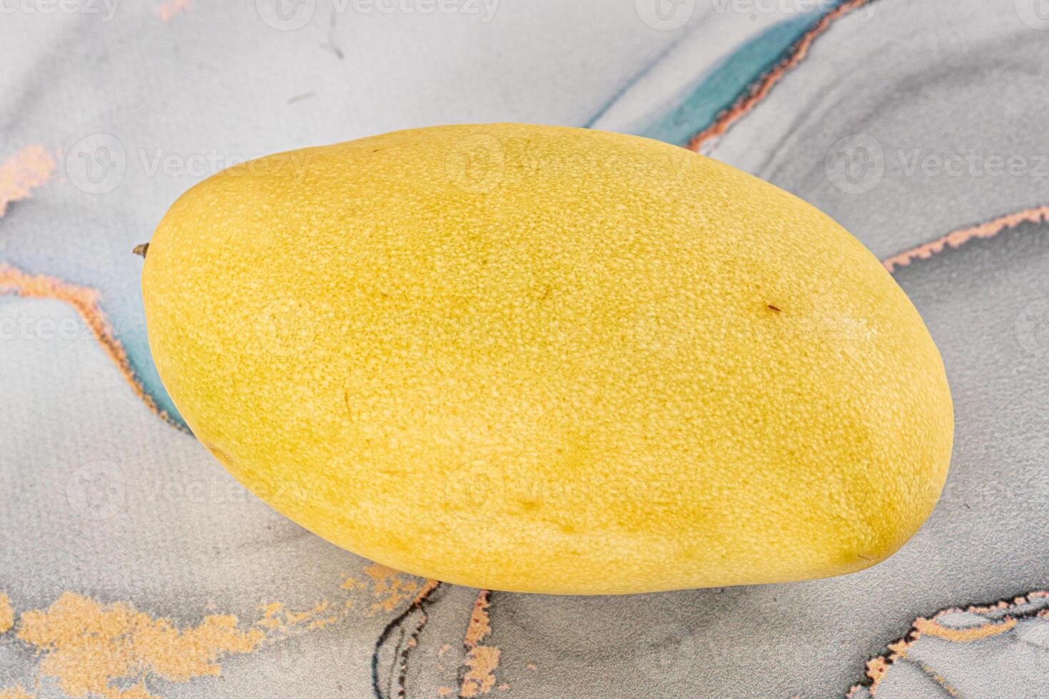 A yellow fruit on a marble surface photo