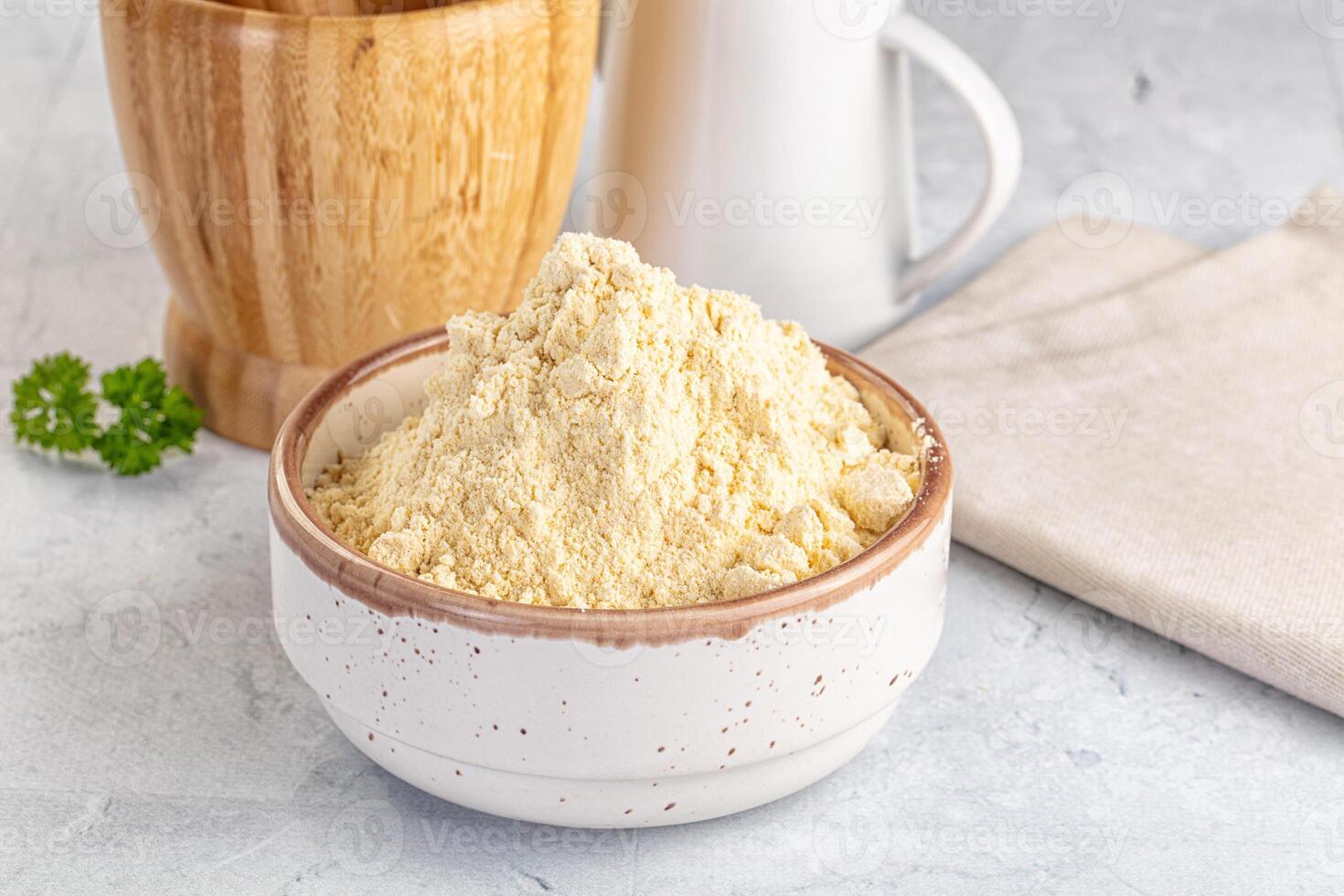 A bowl of flour and a wooden spoon next to a bowl of milk photo
