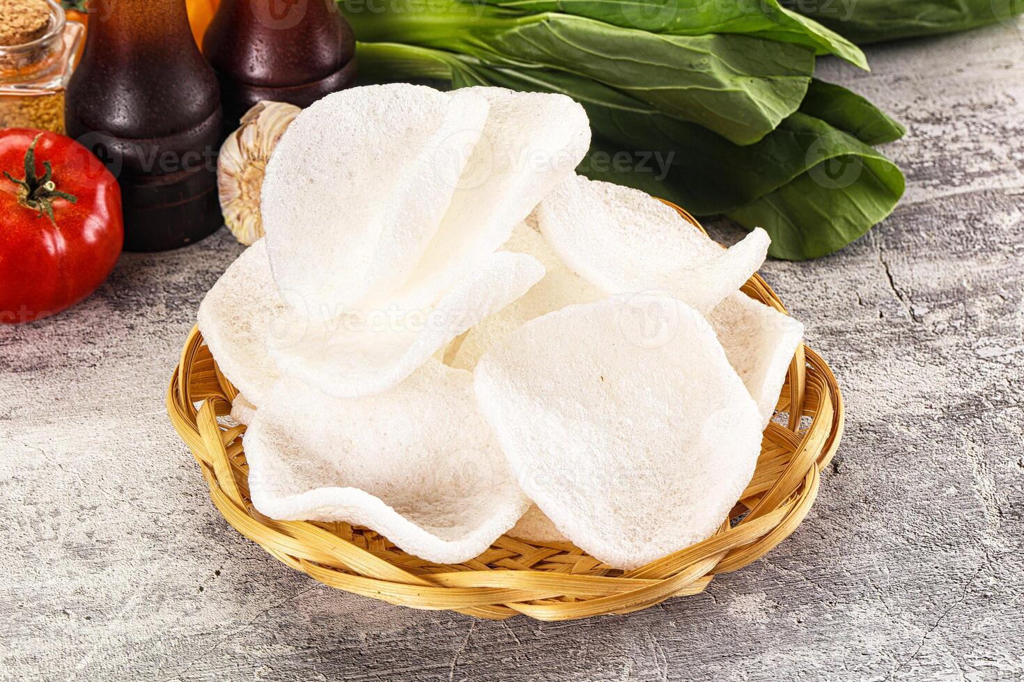 A basket of white chips sitting on a table next to a bottle of ketchup and a bottle photo