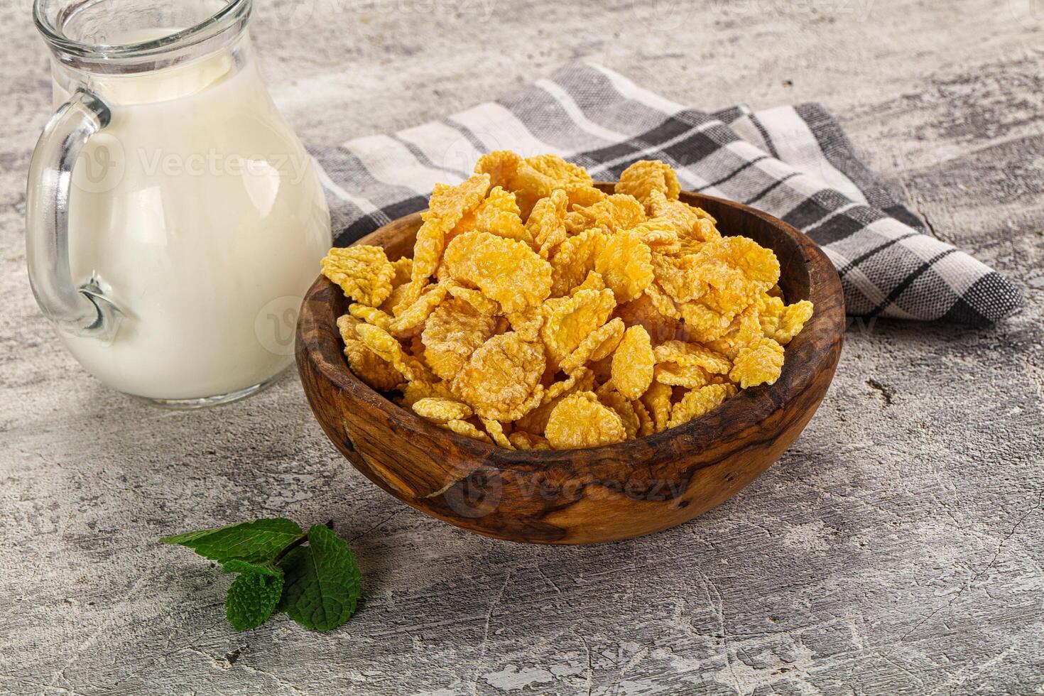Corn flakes and milk in a wooden bowl on a rustic background photo