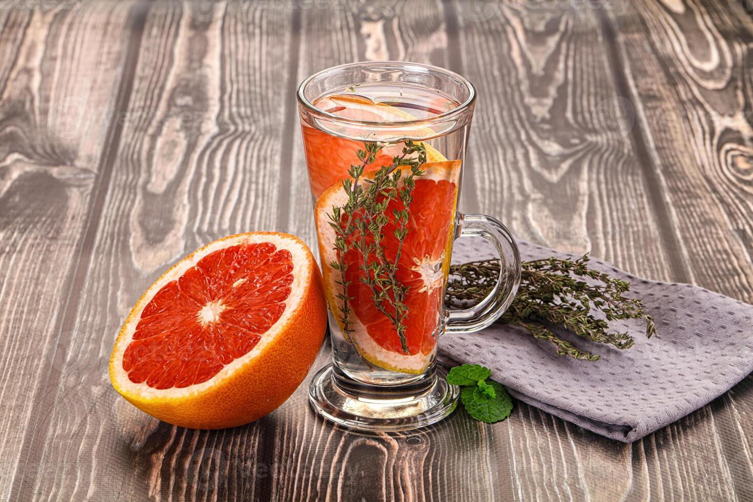 A glass of water with a grapefruit and herbs photo