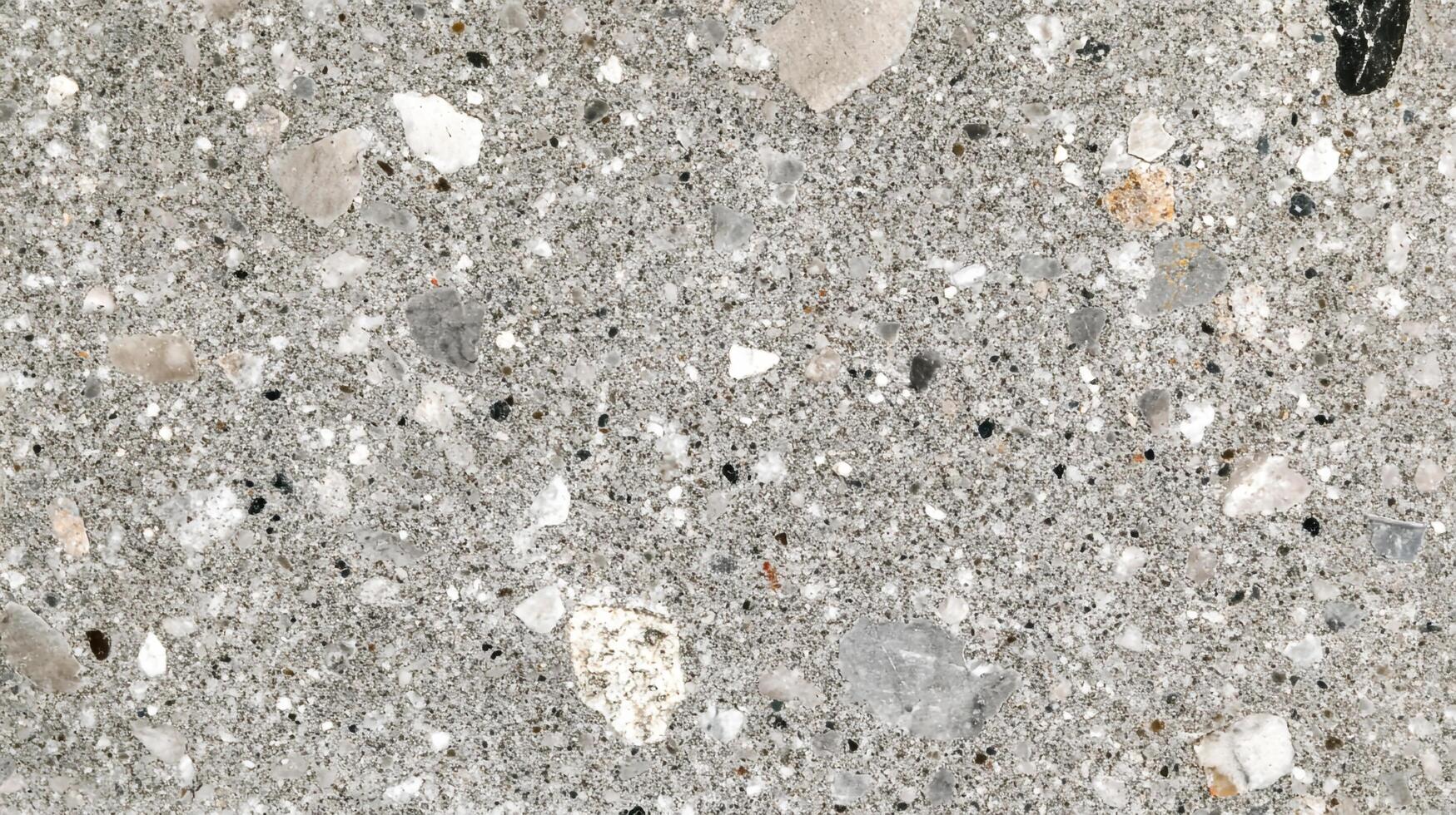 Detailed surface of a gray composite material speckled with small stones and fragments, creating a unique textured appearance. photo