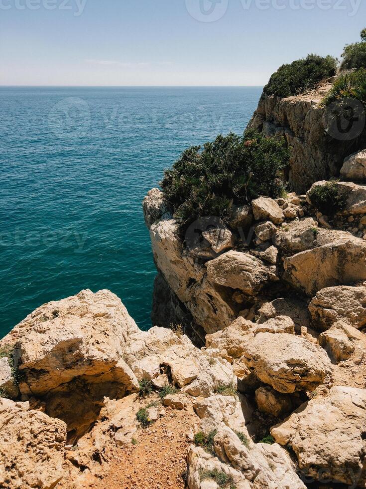 Enjoy stunning coastal view from magnificent rocky cliffside overlooking ocean. Immerse yourself in breathtaking natural beauty found where rocky cliffs meet serene ocean waters. vertical, film look photo