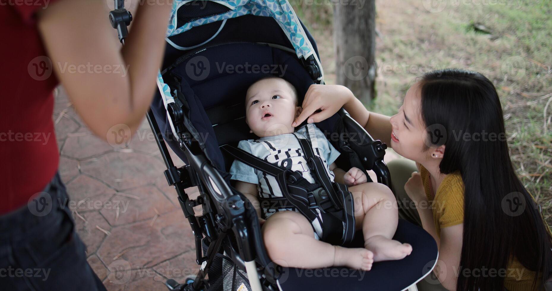 High angle view shot, Two young Asian women play with baby boy in a baby stroller outside a coffee shop. A relaxing atmosphere with a warm moment. photo