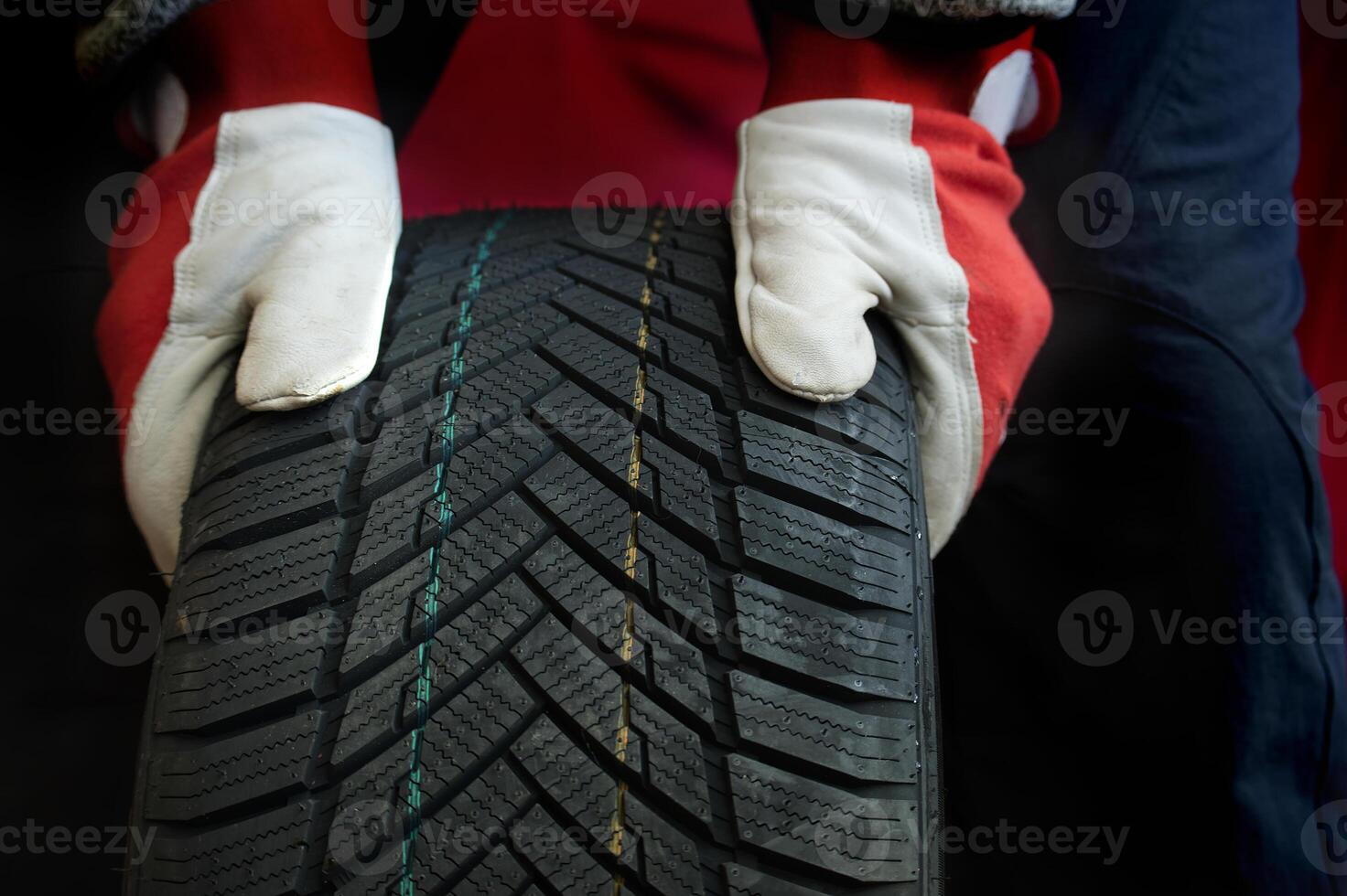 Closeup of a mechanic's gloved hands inspecting tire highlighting tread patterns and automotive care photo
