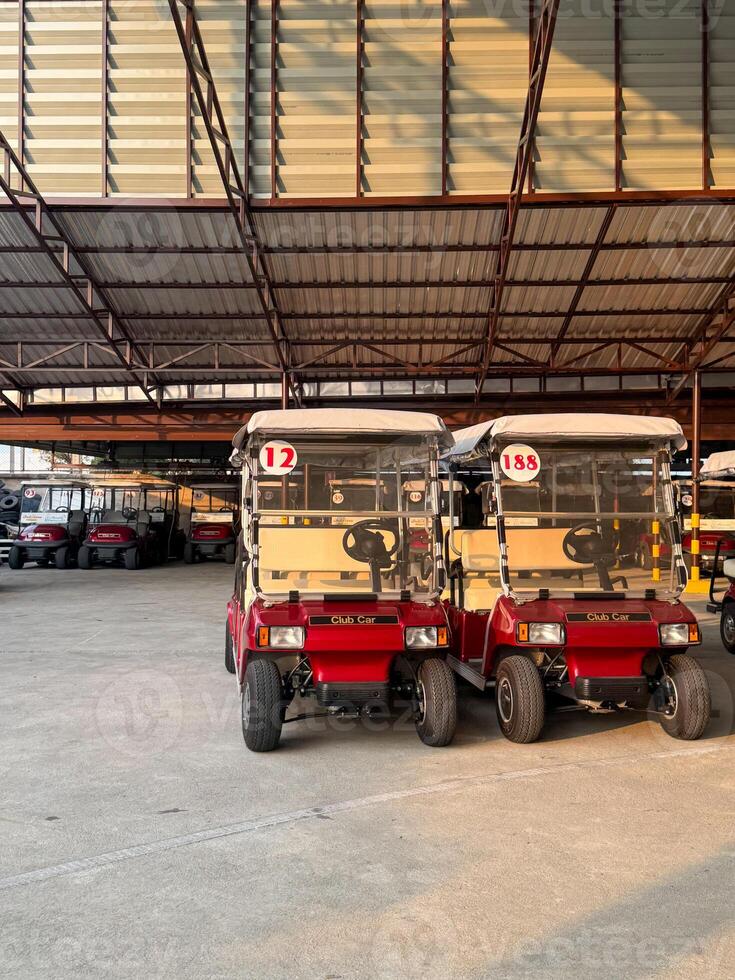 Red electric carts wait for use in a spacious storage area during sunset photo