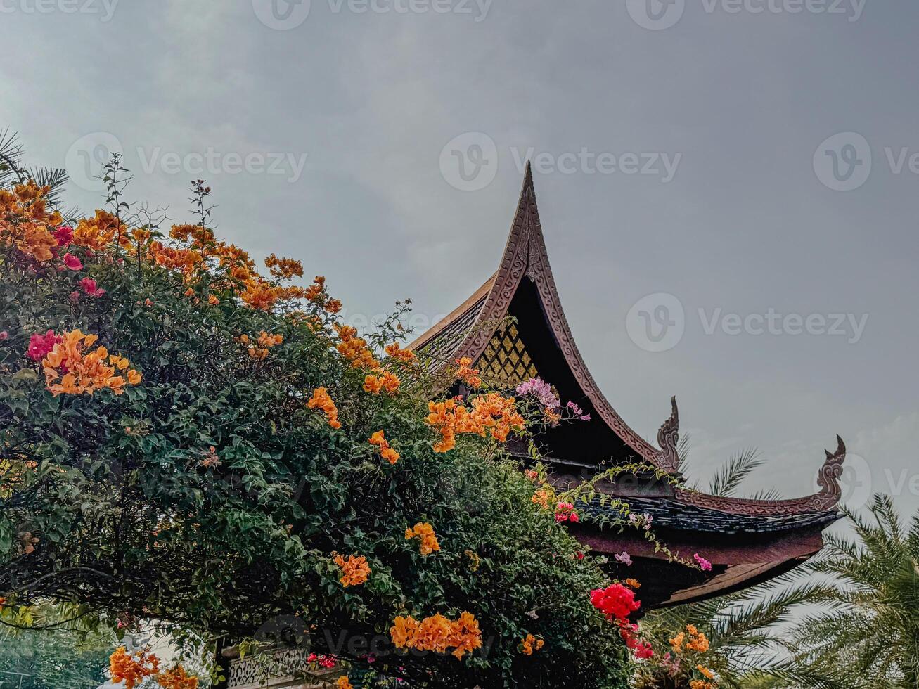 Vivid flowers cascade over a traditional temple roof in a lush garden photo