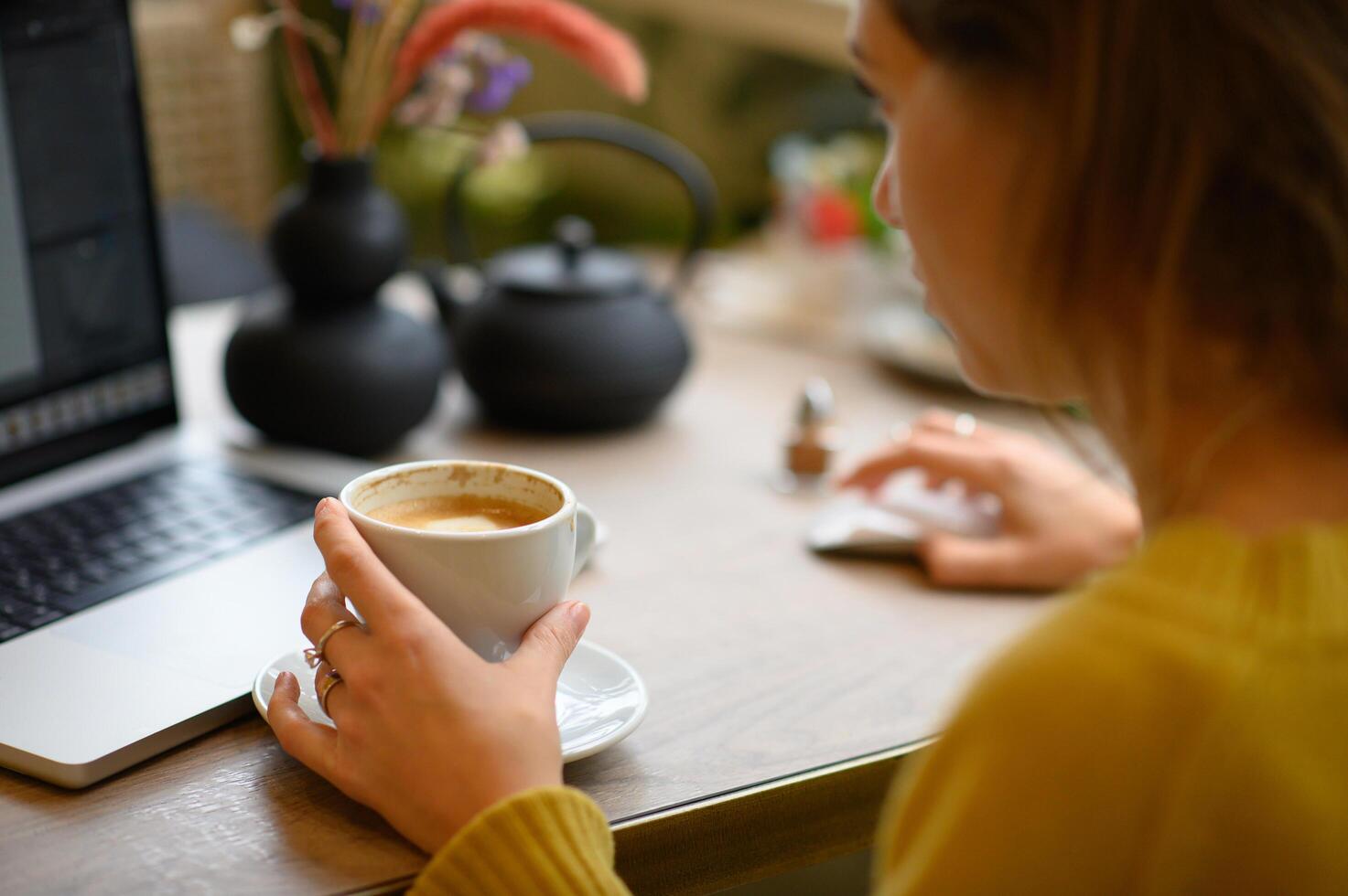 She enjoys a quiet evening at a cafe, immersed in a film playing on her laptop screen. photo