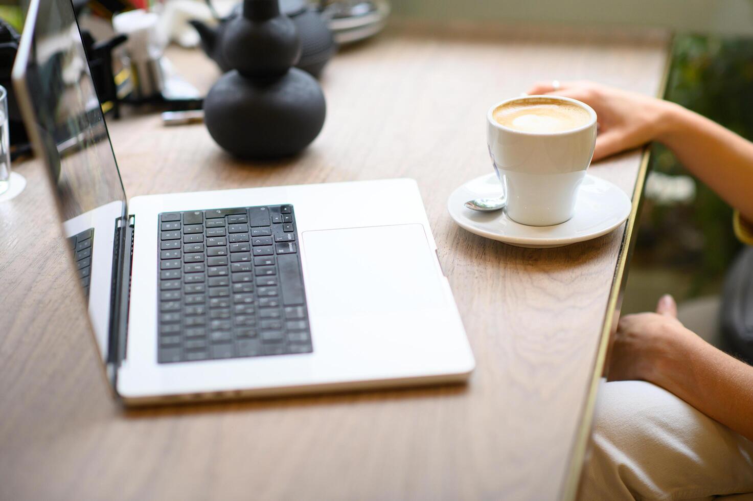 Focused on her work, she sips coffee and types on her laptop in a quiet cafe corner. photo