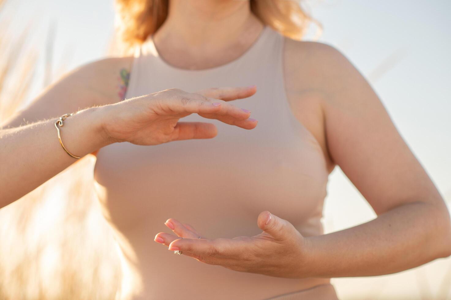 A womans hand gracefully holds a meditation pose, adorned with beads, as soft light enhances the serene and spiritual atmosphere. photo