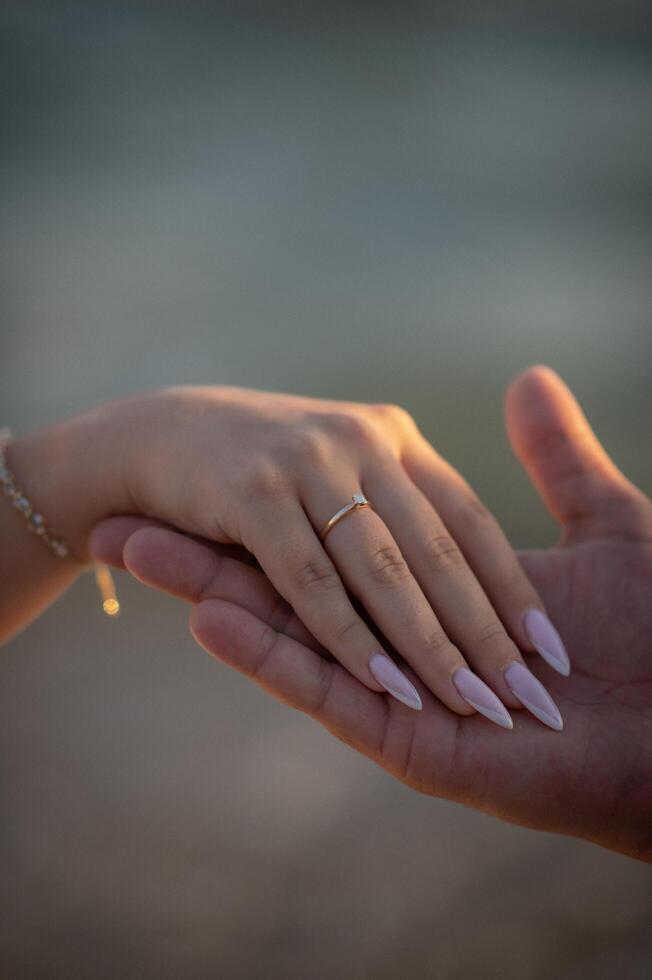 A womans hand with an engagement ring rests gently, the gemstone sparkling as a symbol of love and commitment. photo