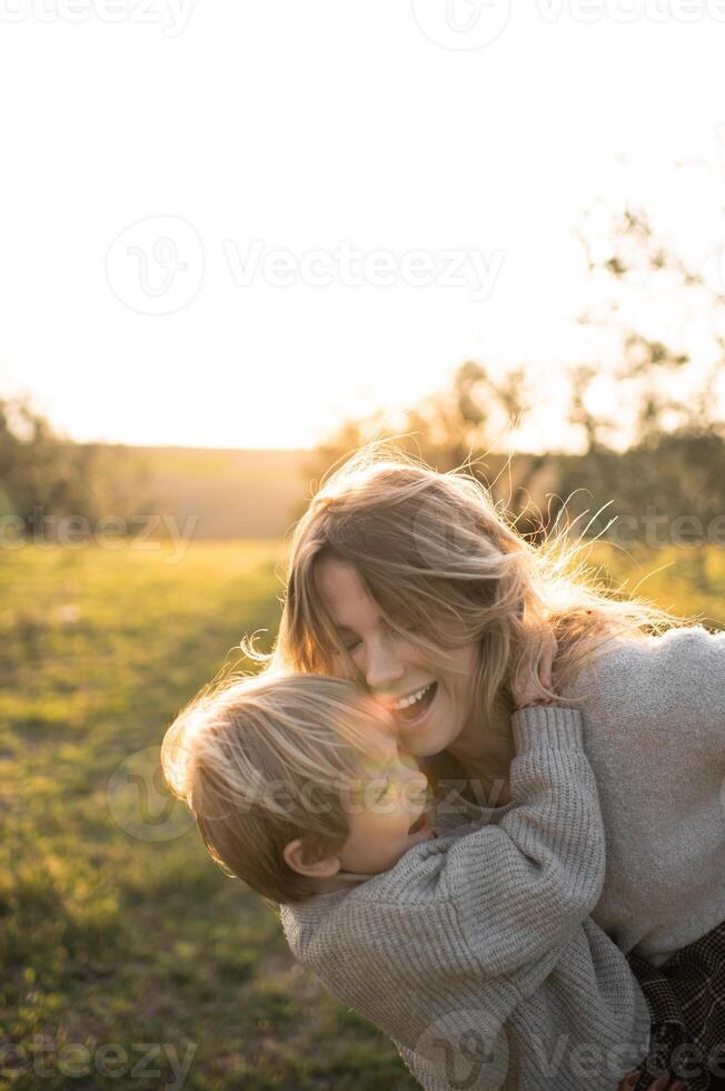 Golden sunlight filters through the olive trees as a mother and son hold each other close. photo