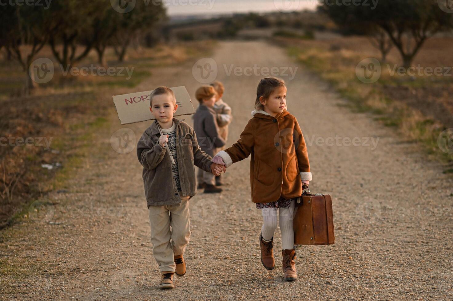 Walking down the road, the kids carry dreams of adventure, their old suitcase and sign hinting at a mysterious journey. photo