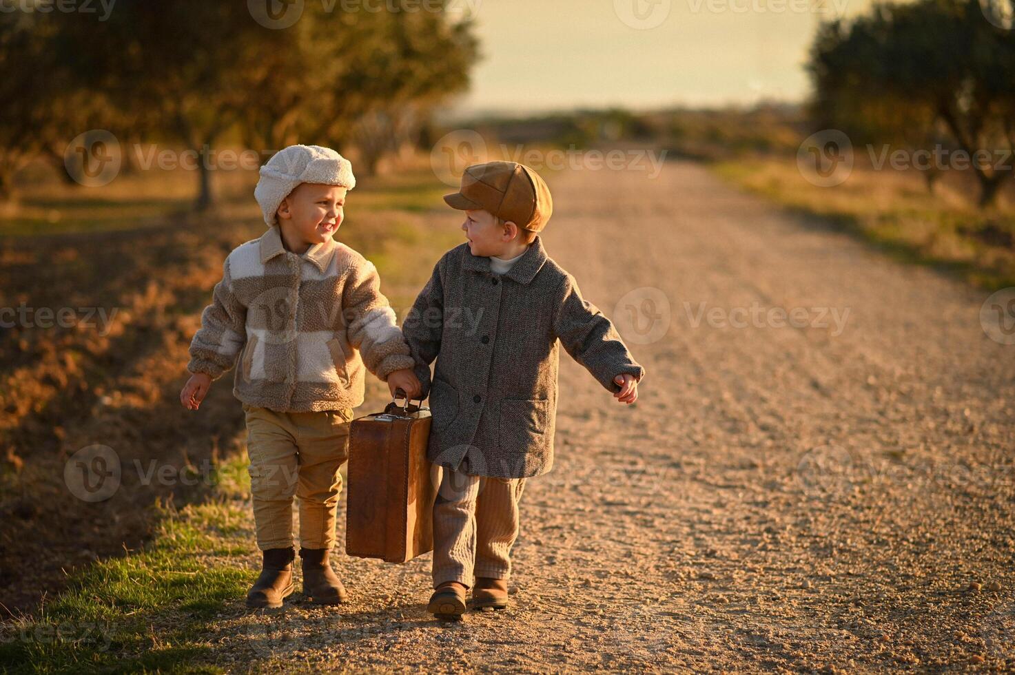 Dressed in old-fashioned outfits, the boys sit on a suitcase by the roadside, like travelers from the past. photo