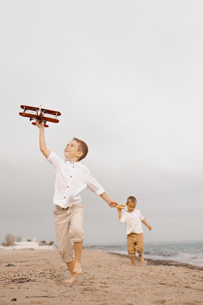 Playing in the sand, the boys raise their toy planes toward the sky, dreaming of soaring through the clouds. photo