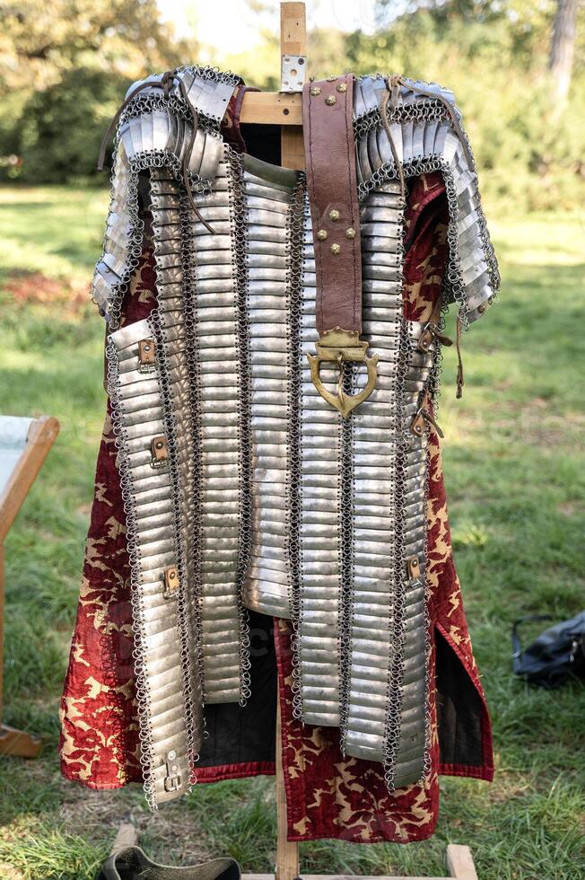 knight's iron armor chainmail made of plates. next to it is a belt with an iron buckle and a red shirt photo