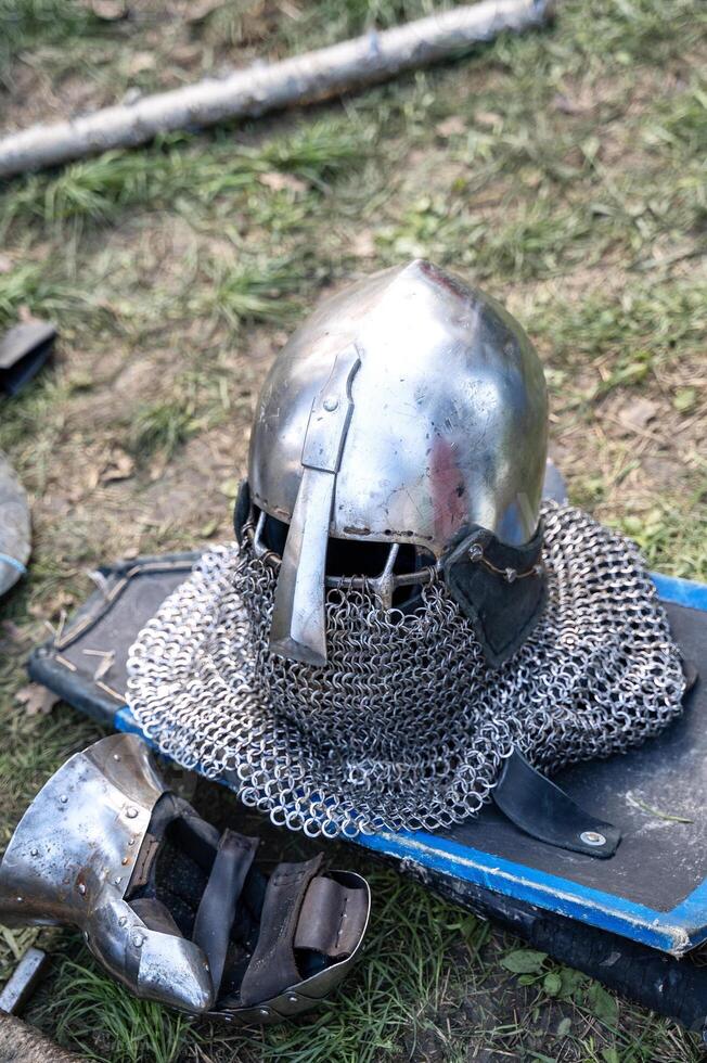 The knight's iron armor lies on the ground. The shield, chain mail, iron gauntlets, weapons of war, and helmet lie on the ground. photo