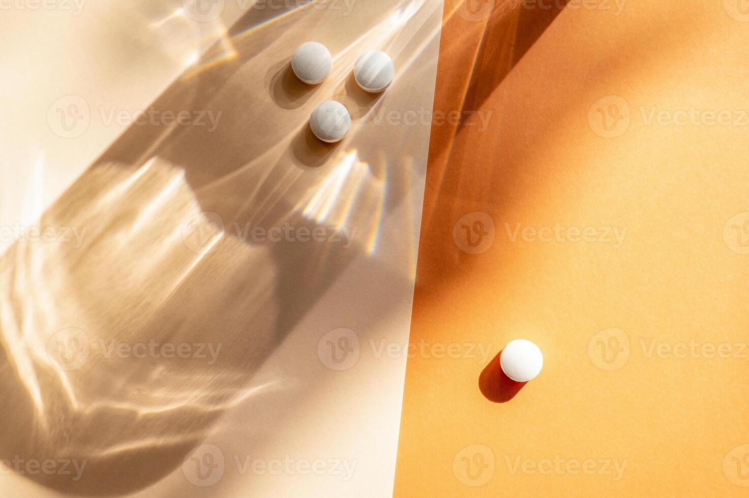 White medical pills lie on the background. A shadow from a glass of water falls on an orange background. Medical concept of daily medication. The pills are white, round. photo