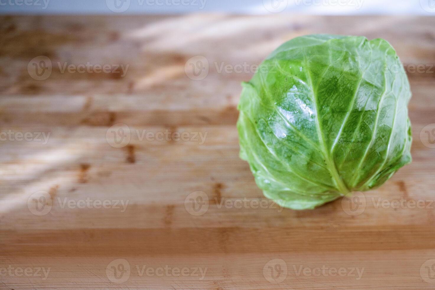 cabbage on a cutting board. whole lies on a cutting board. cabbage young, green lies on a wooden surface. free space on the right photo